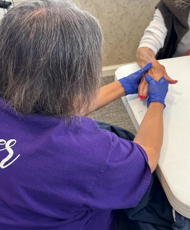 Hospice volunteer gently providing a soothing hand massage and manicure to an elderly resident