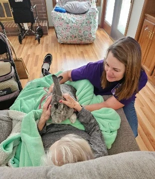 Home Health and Hospice of Kansas volunteer and hospice patient smiling while petting a gentle therapy bunny in Wichita